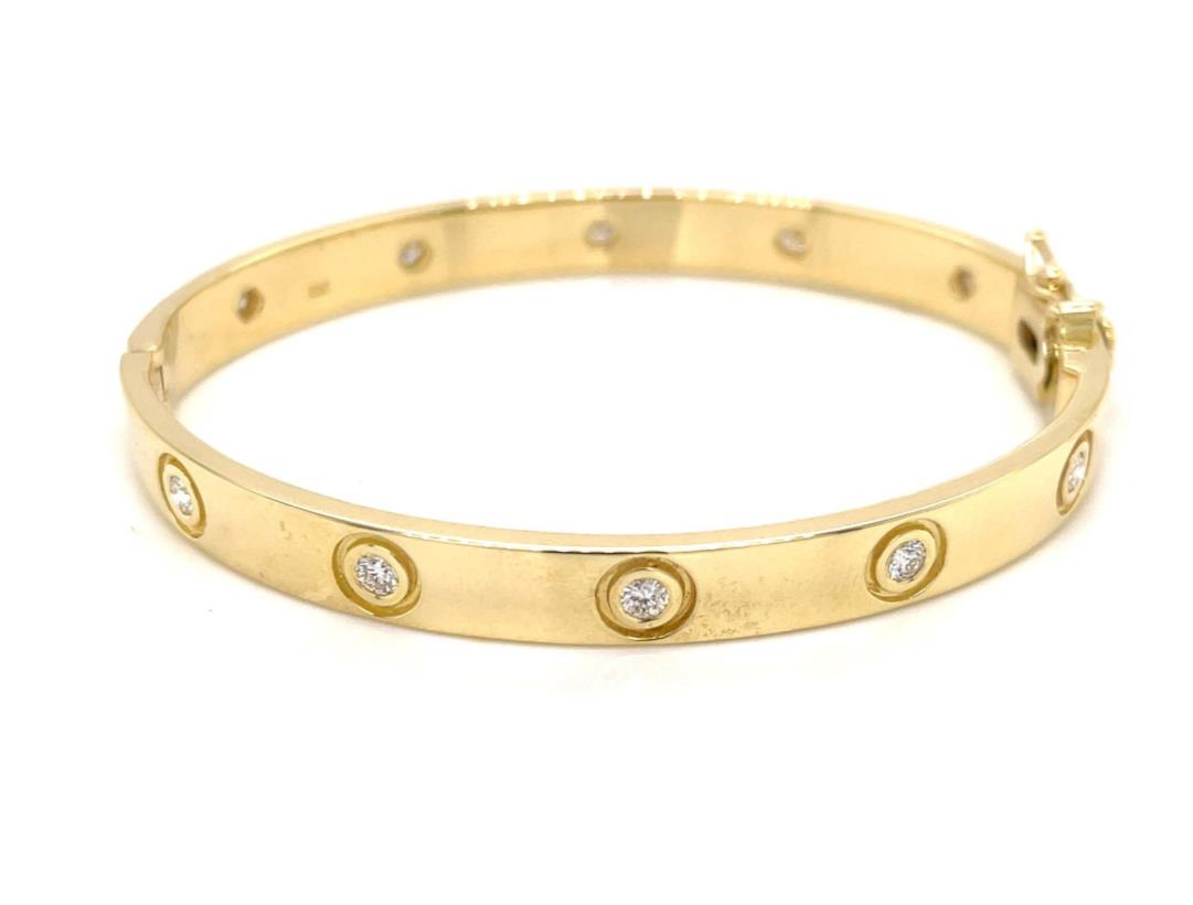 Yellow gold bangle bracelet embedded with circular diamonds along the band.