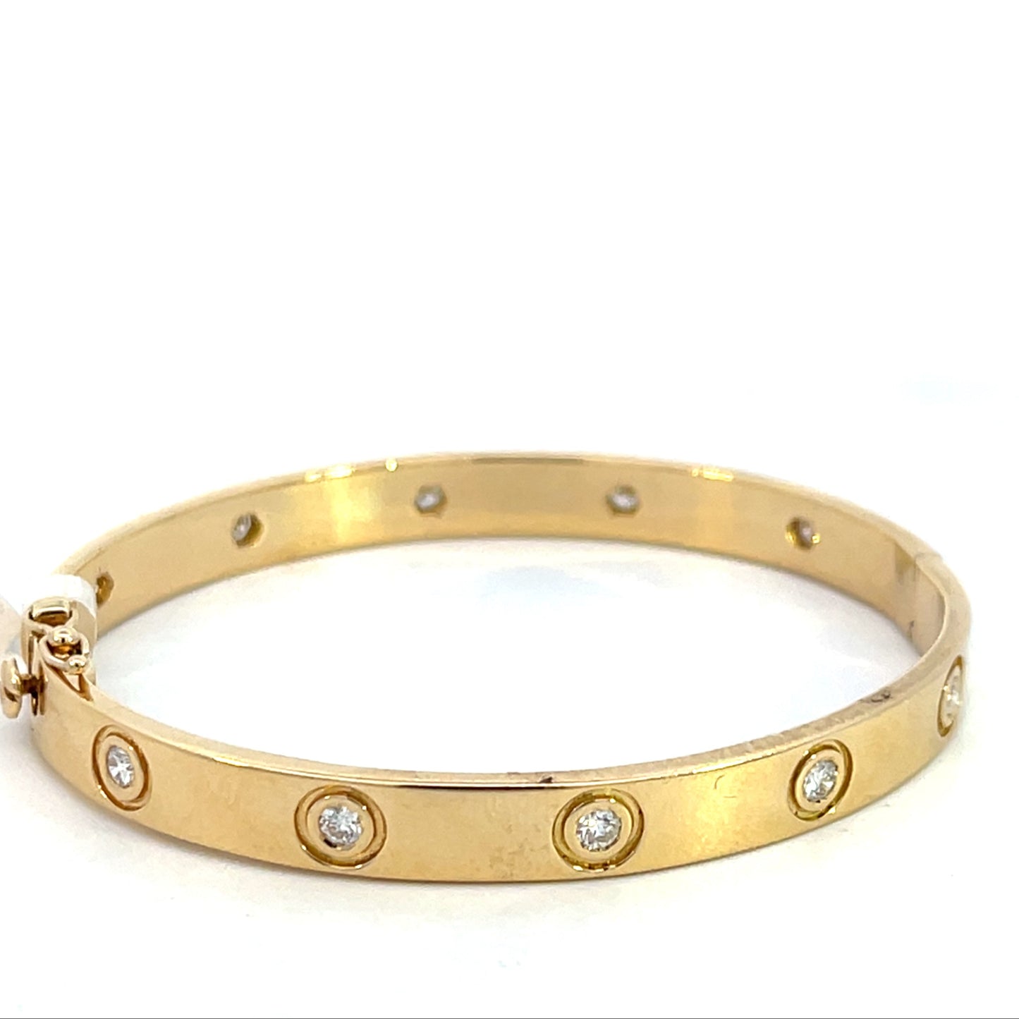 Yellow gold bangle bracelet embedded with circular diamonds along the band.