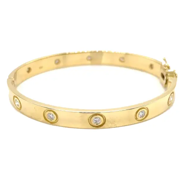 Yellow gold bangle bracelet embedded with circular diamonds along the band.